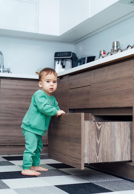 Babyjongen alleen in de keuken Kleine jongen die lade in de keuken opent Peuterjongen in gevaarlijke situatie thuis