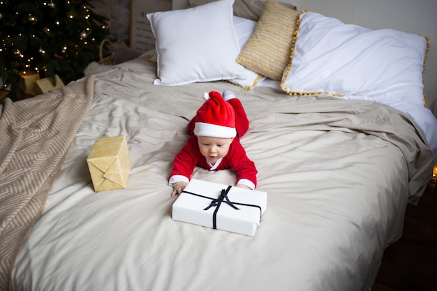 Babyjongen binnen met kerstmisgift op bed thuis