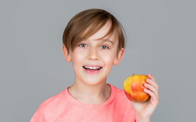 Babyjongen die appel eet en glimlacht Jongen glimlacht en heeft gezonde witte tanden Kleine jongen die appel eet Jongensappels die Kind met appels tonen Portret van een schattig klein kind dat een appel vasthoudt