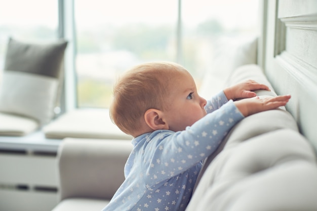 Babyjongen die en op bank thuis kruipen beklimmen