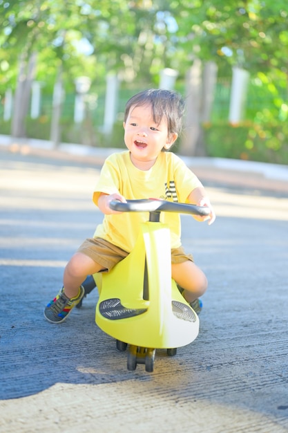 Babyjongen die trycycles berijdt. Kleine Aziatische jongen die tolocar berijdt op de binnenplaats.