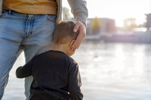 Babyjongen die vadersbeen omhelst. Veiligheid geboden door ouder. Hoge kwaliteit foto