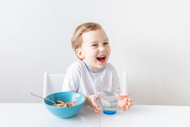 Babyjongen eet thuis met een lepel, het concept van voedsel en voeding voor kinderen