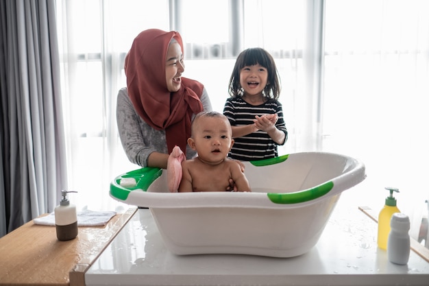Babyjongen gelukkig nemend een bad met moeder en zuster