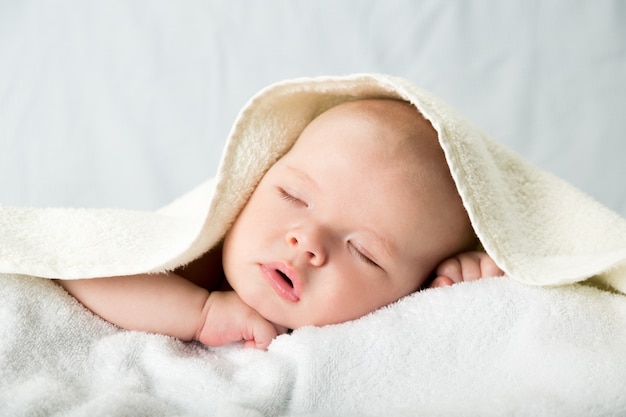 Babyjongen in bed onder de witte deken