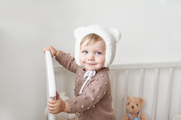 Babyjongen in berenmuts in de kinderkamer Interieur van de kinderkamer Gebreide kinderkleding en accessoires