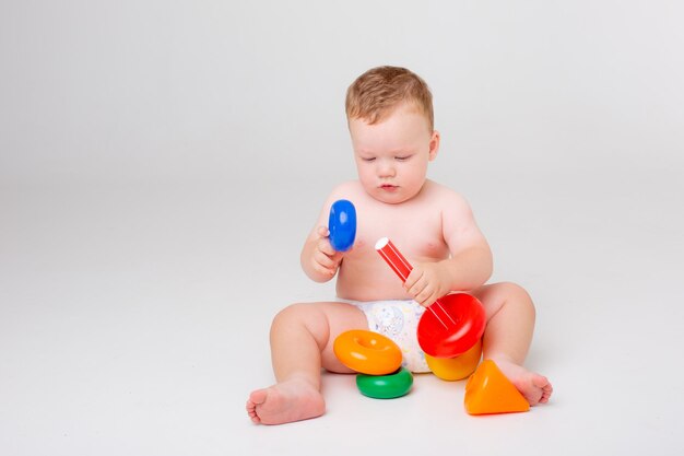 Babyjongen in een luier spelende piramide op een witte studio als achtergrond