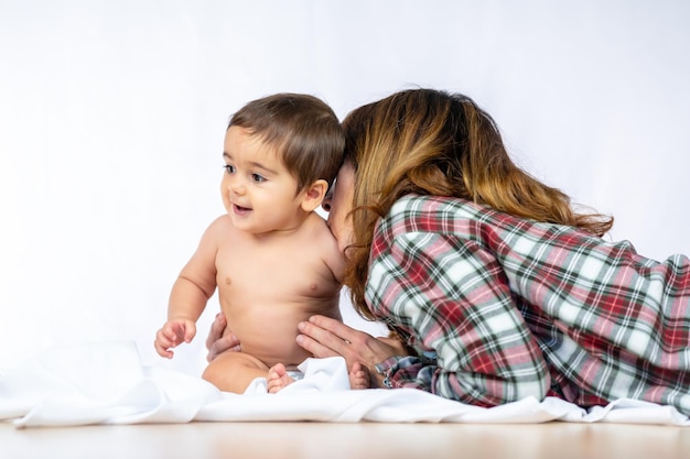 Babyjongen in een studio met een witte achtergrond, acht maanden oude blanke zittend op een heel spannend en mooi moment met zijn moeder