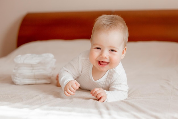 Babyjongen in een witte bodysuit ligt op zijn buik op het bed in de slaapkamer