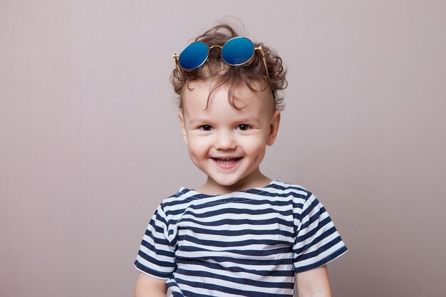 Babyjongen in vest het glimlachen. Grijze achtergrond, studio