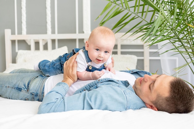 Babyjongen ligt op papa's buik thuis op het bed gelukkig vaderschap of vaderdag