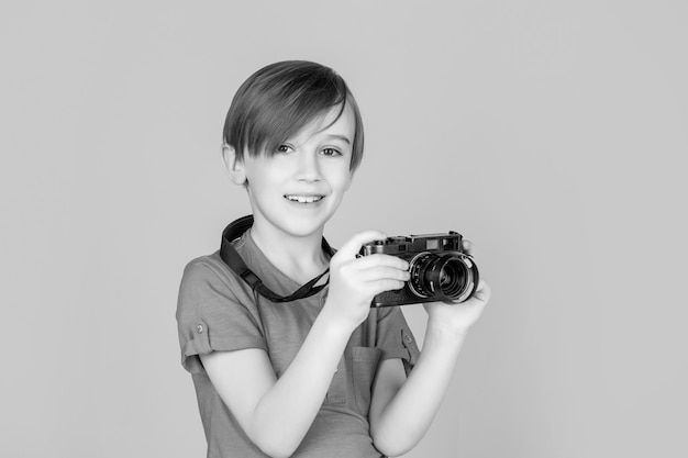 Babyjongen met camera. Vrolijk glimlachend kind dat camera's houdt. Kleine jongen op het nemen van een foto met behulp van een vintage camera. Kind in studio met professionele camera. Jongen met behulp van een camera