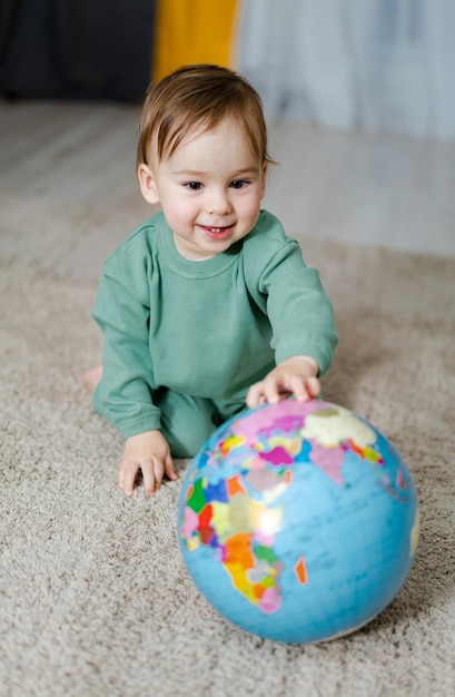 Babyjongen met de geografische wereldbol Kind dat de wereld verkent