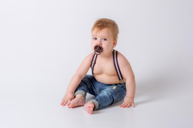 Babyjongen met een fopspeen op een witte achtergrond