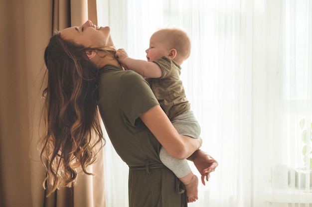 Babyjongen met moeder bij het raam