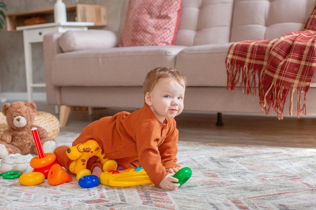 Babyjongen met speelgoed dat thuis op de vloer kruipt