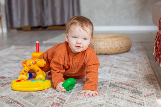 Babyjongen met speelgoed dat thuis op de vloer kruipt