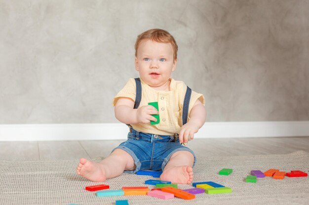 Babyjongen met speelgoed dat thuis op de vloer kruipt