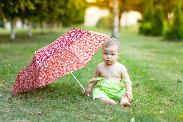 Babyjongen onder paraplu zittend op groen gras gazon in de zomer