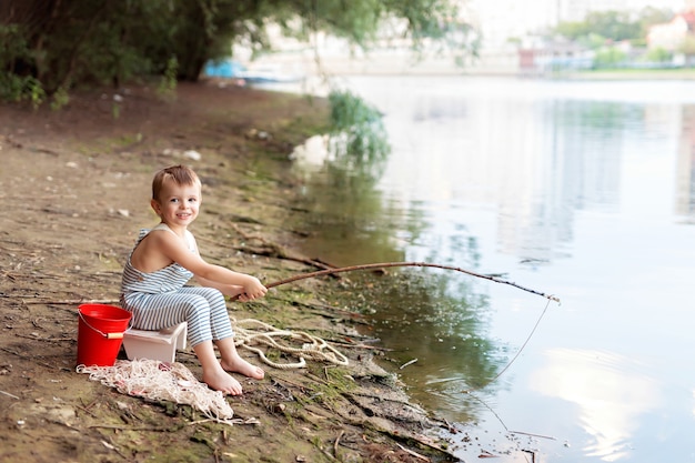 Babyjongen op een zandstrand met een hengel