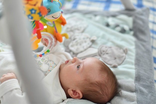 Babyjongen speelt met hangend speelgoed op een ontwikkelingsmat