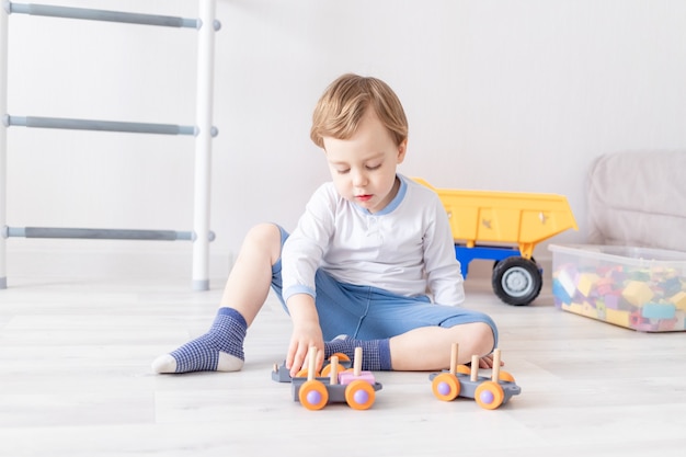 Babyjongen spelen met houten speelgoed thuis op de vloer