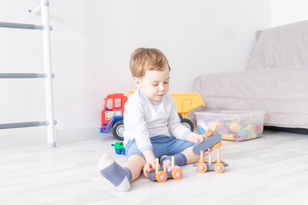 Babyjongen spelen met houten speelgoed thuis op de vloer