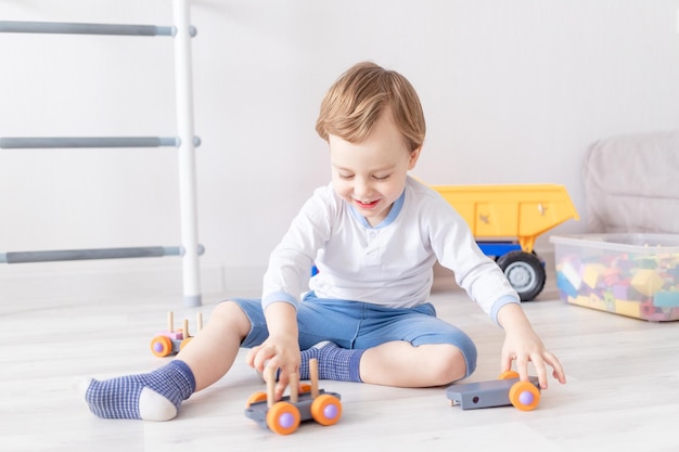 Babyjongen spelen met houten speelgoed thuis op de vloer