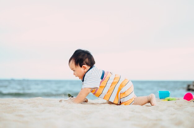 Babyjongen spelen met strand speelgoed met zijn moeder op tropisch strand.