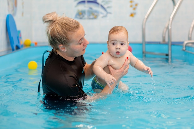 Babyjongen traint om in het zwembad te zwemmen met een trainer