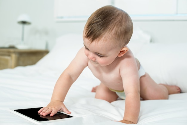 Babyjongen wat betreft digitale tablet op bed thuis