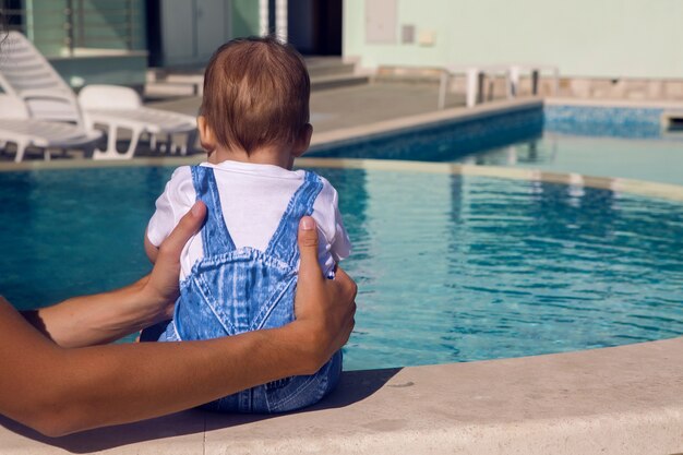 Babyjongen zit bij het zwembad in een denim pak