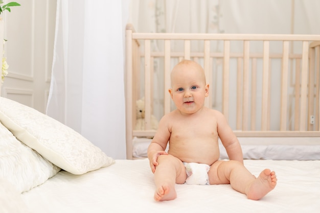 Babyjongen zittend in luiers op een wit bed