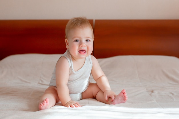 Babyjongen zittend op het bed in de slaapkamer