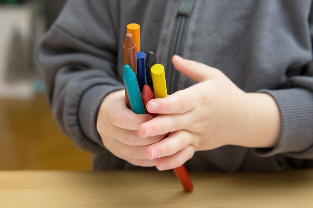 Foto babykind houdt veelkleurige kleurpotloden in zijn handen