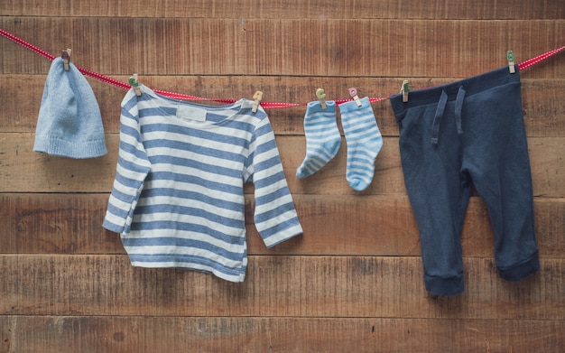 Foto babykleding droogde aan de waslijn en houten achtergrond