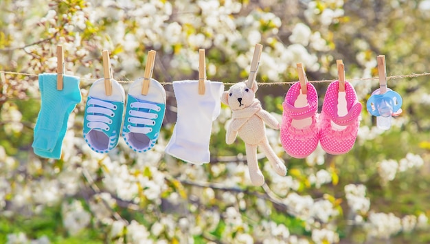 Babykleding en accessoires wegen op het touw na het wassen in de open lucht. Selectieve aandacht.