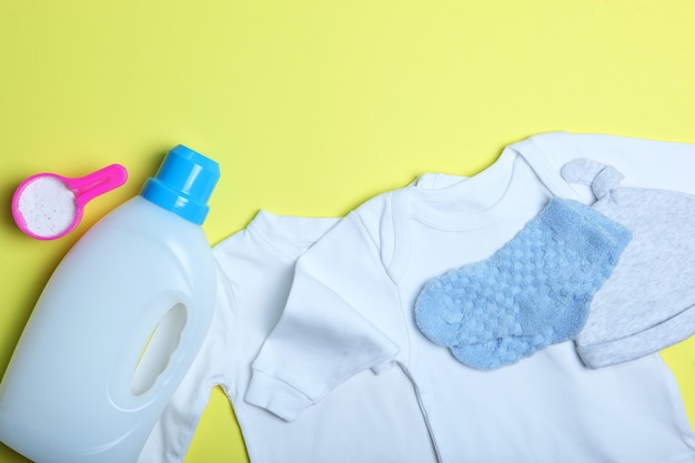 Babykleding en wasmiddelen op een gekleurde achtergrond bovenaanzicht