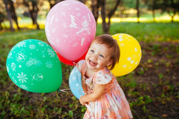 Babymeisje 2-3 jaar oude ballonnen buitenshuis te houden. Verjaardagsfeest. Kindertijd. Geluk.