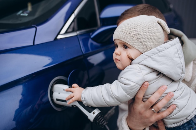 Babymeisje dat elektrische auto oplaadt