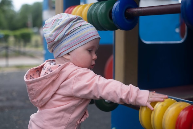 Babymeisje dat met gekleurde ringen op speelplaats speelt