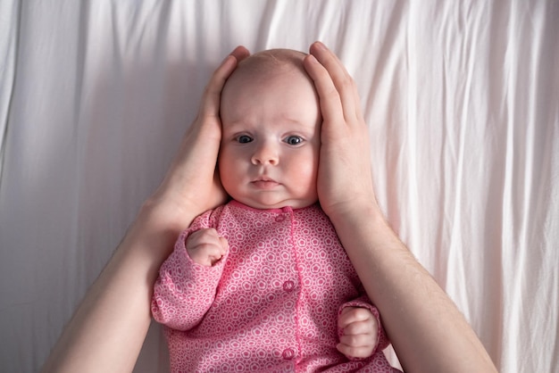 Babymeisje dat moederhand op haar wangen en hoofd drukt