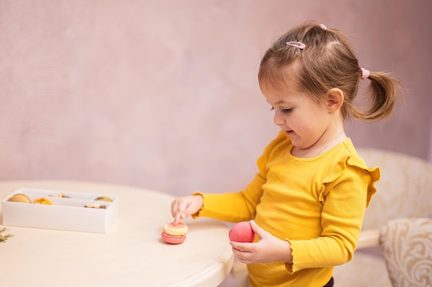 Babymeisje eet heerlijke smakelijke zoete kleur macaron