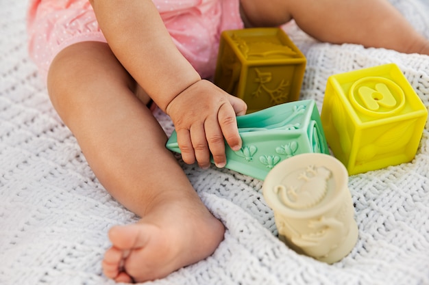 Foto babymeisje het spelen met kleurrijke rubberblokken op witte gebreide deken openlucht bij natuurlijk licht