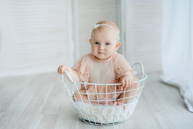 Babymeisje het stellen in een vintage mand. De blik op haar gezicht drukt haar verkenning van de wereld uit.