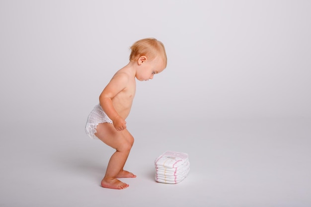 Babymeisje in een luier met een stapel luiers op een witte achtergrond