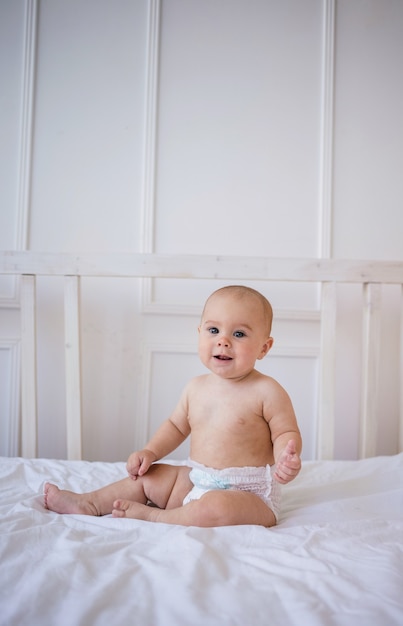 Babymeisje in een luier zit op bamboe beddengoed op het bed