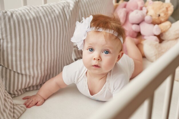 Babymeisje in een wieg met speelgoed in de kinderkamer