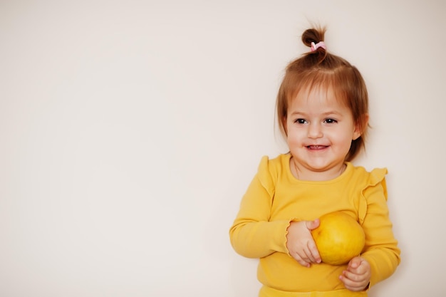 Babymeisje in geel met citroen, geïsoleerde achtergrond.