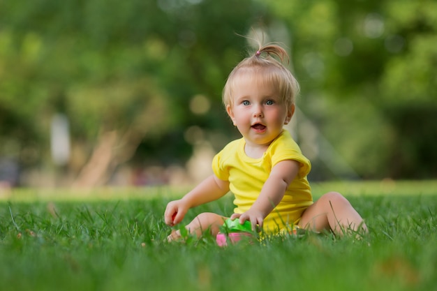 babymeisje in gele Romper op het groene gras spelen piramide